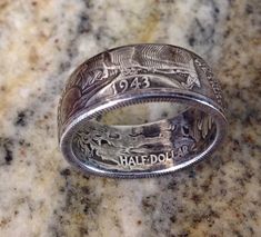 a silver ring with the words half dollar engraved on it sitting on a marble surface