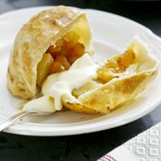 a white plate topped with an apple turnover and whipped cream on it's side