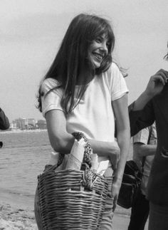 black and white photograph of two women on the beach, one holding a basket with bottles in it