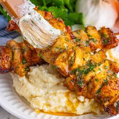 a white plate topped with chicken, mashed potatoes and parsley on top of it