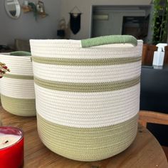 two woven baskets sitting on top of a wooden table next to a candle and potted plant