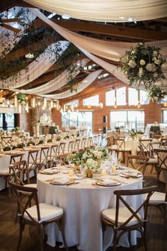 the tables are set up with white linens and greenery for an elegant wedding reception