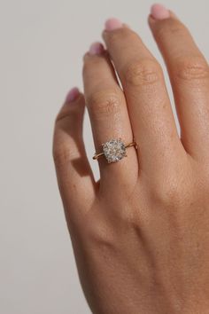 a woman's hand with a diamond ring on top of her finger, against a white background