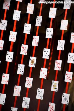 playing cards are lined up on the wall with red ribbons attached to them and tied together