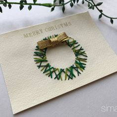 a christmas card with a gold bow on it and green ribbon around the wreath that says merry christmas