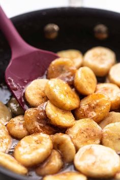 bananas being cooked in a skillet with a red spatula on the side,