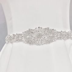 Otylia is elegantly tied with a ribbon, is crafted to radiate brilliance. Embellished with a sparkling crystal medallion, it perfectly complements a simple dress, adding a touch of dazzle to its simplicity. Embellishment measures approximately 12 inches long and 2.4 inches wide Designed with sparkling rhinestones Self-tie with a 106" ribbon Made-to-order, ships within 1 week from NY