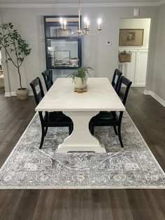 a dining room table with chairs and a rug on the floor in front of it