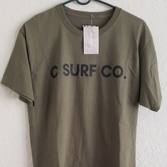 Size M C Surf T Shirt Brand New With Tag Dark Green In Color Casual Relaxed Fit Shirt For Surfing, Casual Pre-shrunk Surfing T-shirt, Casual Pre-shrunk T-shirt For Surfing, Cotton Surfing T-shirt With Screen Print, Cotton Screen Print T-shirt For Surfing, Cotton T-shirt With Screen Print For Surfing, Casual Short Sleeve Surfing Shirt, Casual Surfing Top With Graphic Print, Casual Cotton Surfing T-shirt