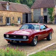 a red car parked in front of a stone building