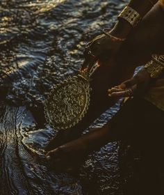 a person standing in the water with some kind of thing on their hand and wearing bracelets