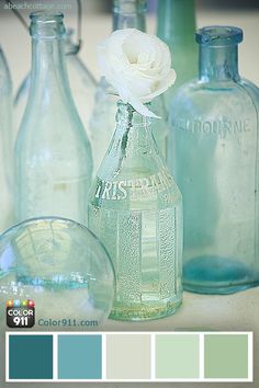 there are several glass bottles on the table with flowers in them and color swatches