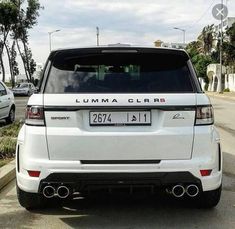 the back end of a white car parked in front of a street