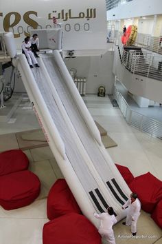 two people are playing on an inflatable slide at the mall with red bean bags