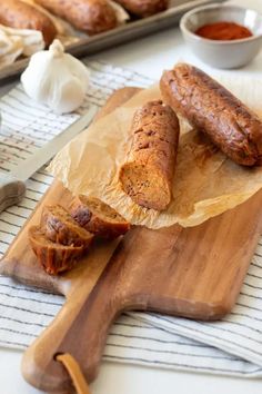 two sausages are on a cutting board next to some garlic