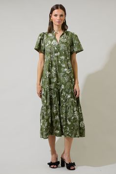 The Hazleton Floral Britt Poplin Tiered Midi Dress is one of kind. This midi dress has short sleeves that frame a split neckline with ruffles around and a lower button up detail. It has belt around the waist and tiered layers. You can easily style it with wedges or strappy heels.- Tie sash- Pockets- Tiered- Puffed short sleeves- Color: Cream OliveSize + Fit - Model is 5'10" and wearing size XS- Measurements taken from size S - Chest: 20"- Length: 49 1/2" Fabric Self: 100% Cotton Style Number STD Cotton Short Sleeve Midi Dress For Garden Party, Cotton Midi Dress With Short Sleeves For Garden Party, Short Sleeve Midi Dress With Ruffle Hem For Daywear, Short Sleeve Ruffled Midi Dress For Daywear, Green Short Sleeve Dress With Ruffle Hem, Cotton Midi Dress With Ruffles And Short Sleeves, Green Tiered Midi Dress For Daywear, Cotton Midi Dress With Ruffle Hem And Short Sleeves, Tiered Midi Dress