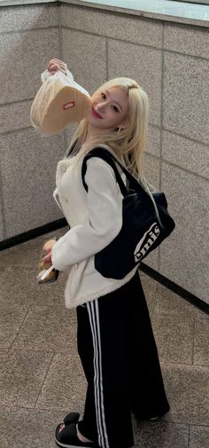 a woman with blonde hair carrying a bag