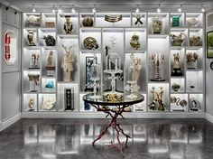 a room filled with lots of different types of vases and artwork on display behind glass shelves