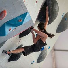 a woman climbing up the side of a wall with rock climbing equipment on her feet