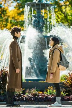 two people standing in front of a fountain