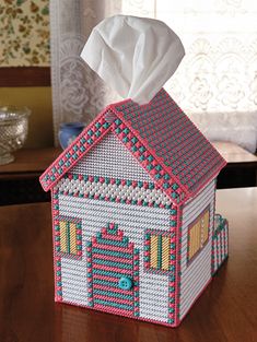 a tissue dispenser with a house design on it sitting on a table