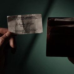 a person holding up a business card in front of a green wall with the name miller's school on it