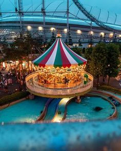 an amusement park with a carousel and water slide at night, lit up by lights