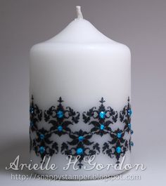 a white candle with blue and black designs on it's side, sitting in front of a gray background