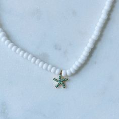 Dainty beaded necklace with small white seed beads and a dainty turquoise gem-paved gold starfish charm. Necklace is about 14 inches and includes a 2 inch extender. White Starfish Beaded Necklaces For Beach, White Adjustable Necklace With Starfish Charm, White Beaded Necklaces With Starfish Charm For Beach, Adjustable White Necklace With Starfish Charm, White Starfish Necklace With Starfish Charm, Adjustable White Starfish Necklace, White Starfish Charm Necklace, White Adjustable Starfish Necklace, White Star Beaded Necklace With Star Charm