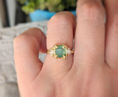 a woman's hand holding a ring with a green tourmaline stone in it