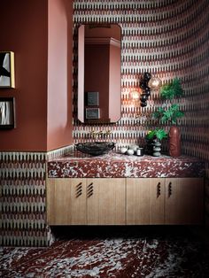 a bathroom with a sink and mirror next to a wallpapered wall that has an abstract pattern on it