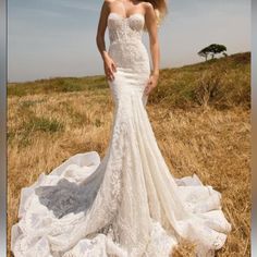 a woman in a white wedding dress standing on a field with her hands on her hips