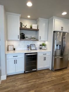 a kitchen with white cabinets, stainless steel appliances and wood flooring is seen in this image