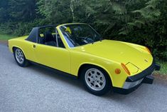 a yellow sports car is parked on the side of the road in front of some trees