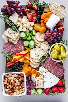 a platter filled with cheese, crackers, fruit and nuts