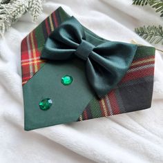 a close up of a tie with a green bow on it and some christmas tree branches in the background