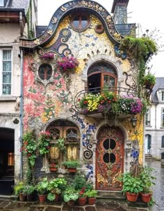 a building with many windows and flowers on the outside, along with potted plants