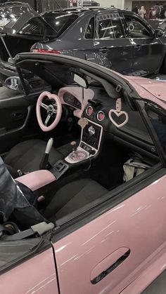 the interior of a pink convertible car at a showroom