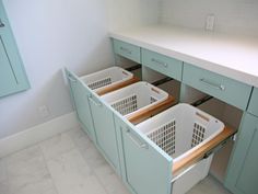 two laundry baskets are in the middle of a kitchen cabinet with drawers on both sides