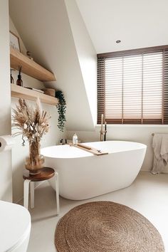 a white bath tub sitting in a bathroom next to a window with blinds on it