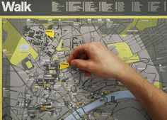 a hand is pointing at a map with yellow lines on it and the words walk written in black