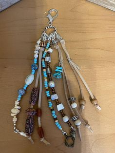 several necklaces are hanging on a wooden table next to a keychain with beads and charms