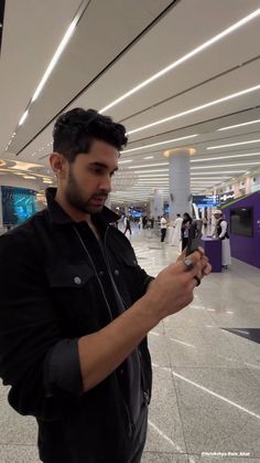 a man standing in an airport looking at his cell phone