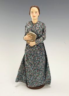 a figurine wearing a dress and holding a book