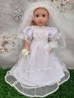 the doll is wearing a white dress and veil with flowers in her hand, standing on grass