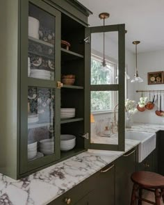 a kitchen with green cabinets and marble counter tops