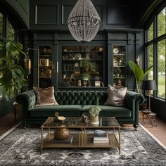 a living room with green couches and chandelier hanging from the ceiling in front of large windows