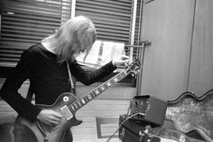 a man with long hair playing an electric guitar in front of a recording equipment set