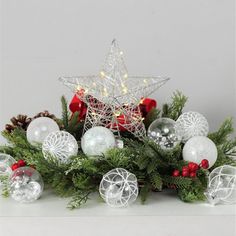 an arrangement of christmas ornaments and decorations on a white surface with a star in the center