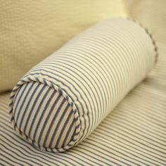 a close up of a pillow on a bed with blue and white striped fabric,